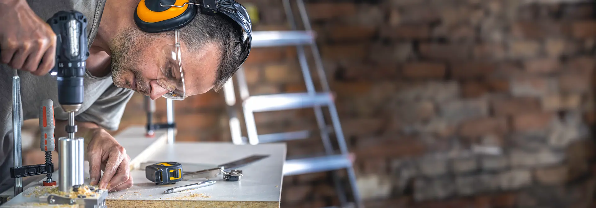 Man wearing safety goggles using a power tool on a workbench